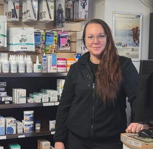 Kvinna med långt hår och glasögon står framför en butikshylla